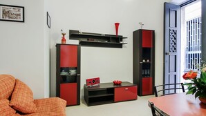 Een woonkamer met een bank, salontafel, tv-meubel en een eettafel.