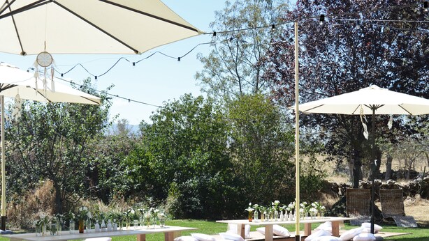 Une terrasse extérieure avec des tables et des chaises, une piscine et des guirlandes lumineuses.