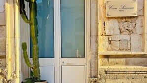 Une porte avec un panneau de verre, un cactus en pot et une plaque de pierre portant une inscription.