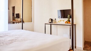 Une chambre d’hôtel moderne avec un lit à baldaquin, une petite table avec un téléviseur et un miroir.