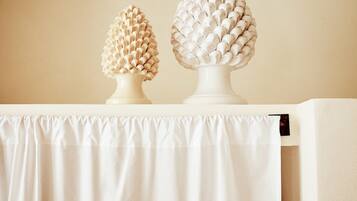 Two white decorative vases on a white table against a beige wall.
