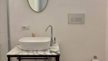 A bathroom with a white sink, mirror, and toilet.