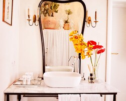 Un baño con lavamanos blanco, espejo y dos apliques de pared.