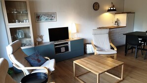 Een moderne woonkamer met een televisie, zitmeubels, een salontafel en een eethoek.