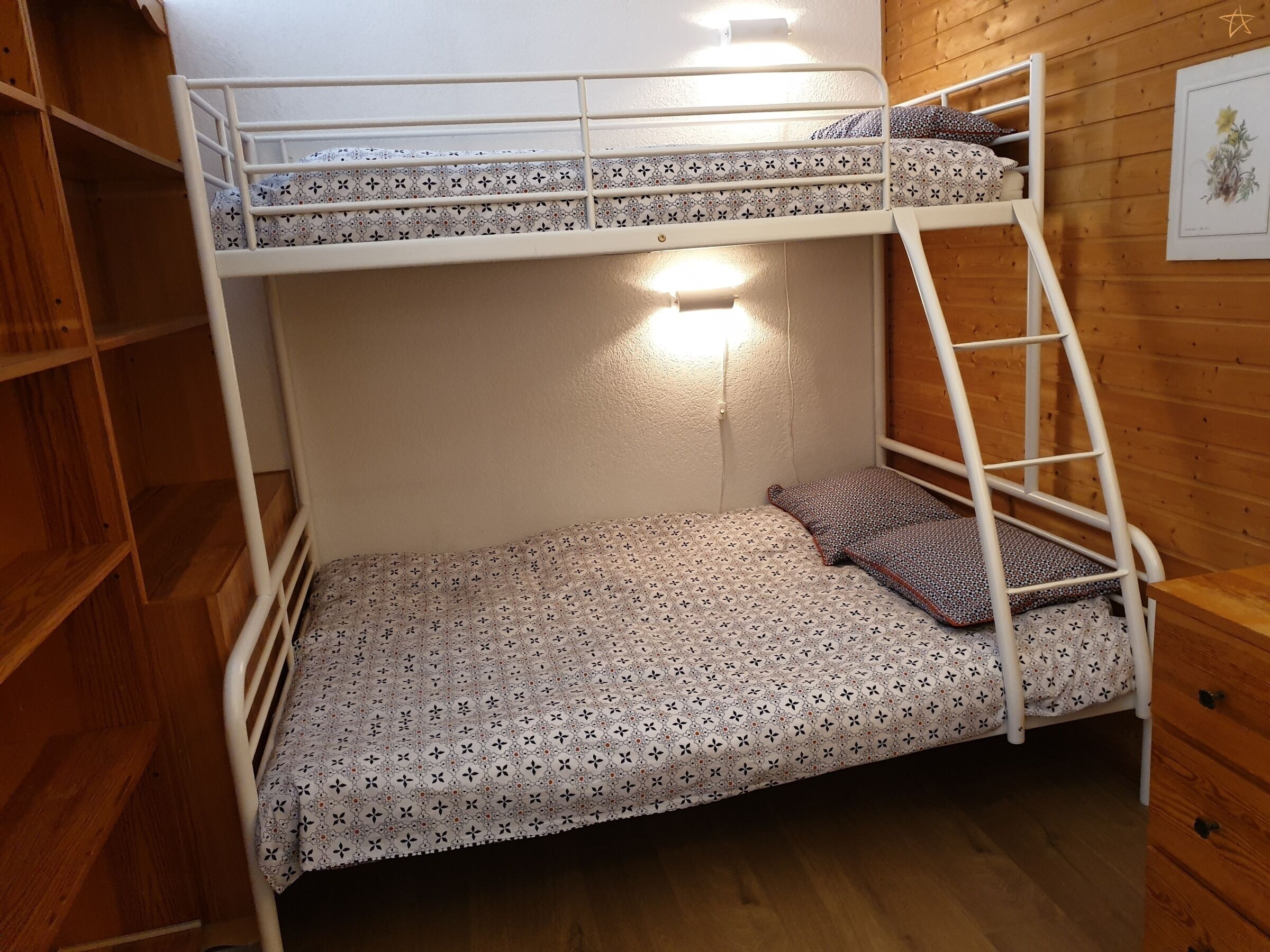 Una litera con escalera, estante y luz adosada a la pared.