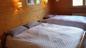 Een houten kamer met slaapkamer, met twee bedden, elk voorzien van beddengoed met patronen en wandlampen.