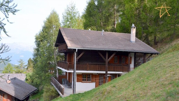 Un edificio de estilo chalet con tejado inclinado, balcones de madera y una chimenea.