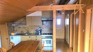 Una cocina compacta con armarios de madera, una estufa y una mesa de comedor con sillas.