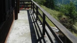 A wooden balcony with a view of mountains and a clear sky. - Outdoor parking space - close to the cottage (at the start of the stairs) (St-Luc)