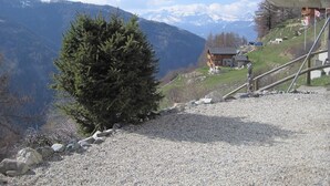 A mountain view with a house and a small tree in the foreground. - Outdoor parking space - close to the cottage (at the start of the stairs) (St-Luc)