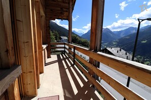 A wooden balcony with a view of a mountain landscape.