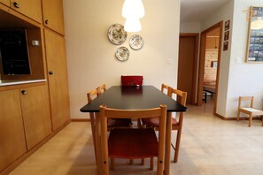 Ein Essbereich mit einem schwarzen Tisch, Holzstühlen und einer roten Bank. An der Wand hängen drei dekorative Teller.