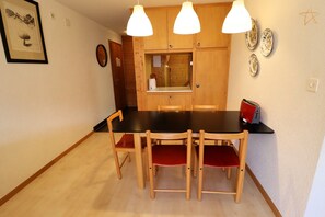 A dining area with a black table, wooden chairs, and pendant lights.