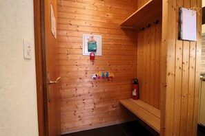 A wooden sauna with a bench, a wall-mounted heater, and a fire extinguisher.