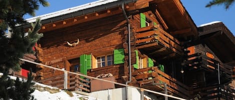 Eine Holzhütte mit Balkonen und einem mit Schnee bedeckten Dach.