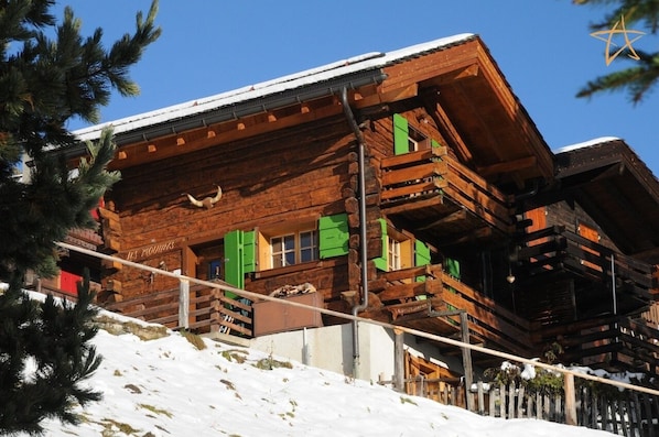 Una xalet de fusta amb balcons i un teulat cobert de neu.