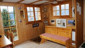 Eine Holzhütte mit einer Bank, Holzregalen und gerahmten Bildern.