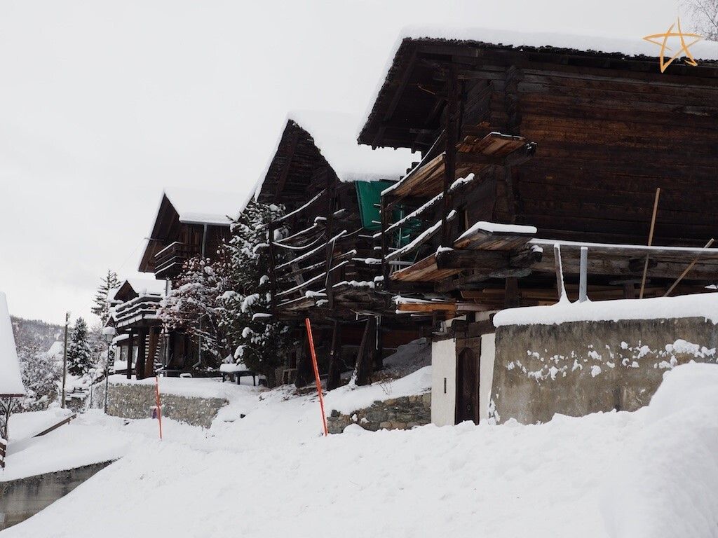 Een met sneeuw bedekte houten constructie met een schuin dak, omgeven door sneeuw.