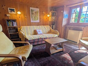 A cozy room with a sofa, a chair, a small table, a bookshelf, and a radiator. - Outside: individual chalet on 3 floors for max. 5 people in the center of the old village with direc (St-Luc)