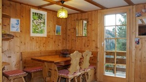 Ein Holzinterieur mit einem Esstisch, Stühlen und einem großen Fenster.