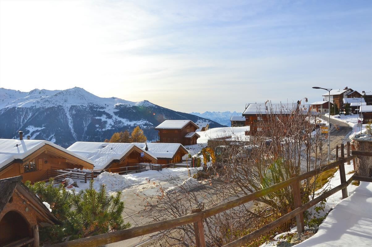 A snow-covered mountain village with wooden cabins and a clear view of the mountains.