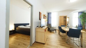 A modern, well-lit room with a bed, a desk, and a dining area. - Apartment No. 03 in Vienna near Schönbrunn/Westbahnhof | Keyless Check-In (Rudolfsheim-Fünfhaus)
