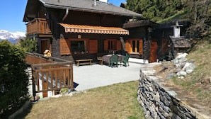 A wooden chalet with a balcony, a stone wall, and a view of mountains. - Chalet VOLIÈRE HAUT -Outside : chalet for 8 persons, large terrace, garden, balcony, barbecue, sun t (St-Luc)