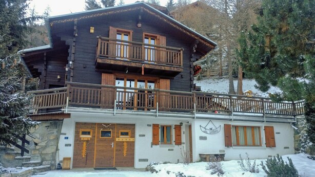 A two-story wooden chalet with a balcony, stone foundation, and a sign reading "La Voliere". - Chalet VOLIÈRE HAUT -Outside : chalet for 8 persons, large terrace, garden, balcony, barbecue, sun t (St-Luc)