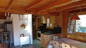 A cozy cabin-style kitchen with wooden walls, a stove, and a dining area with heart-shaped chairs. - Chalet VOLIÈRE HAUT -Outside : chalet for 8 persons, large terrace, garden, balcony, barbecue, sun t (St-Luc)