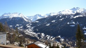 A mountain landscape with snow-covered peaks and a cabin in the foreground.