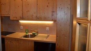 A kitchen with wooden cabinets, a stainless steel sink, and a dish soap bottle.