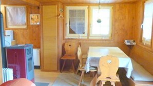Una baita in legno con zona pranzo, angolo cottura e finestra vista panoramica.