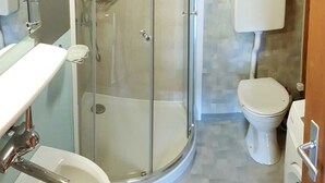 Un bagno con doccia vetro, water e lavandino.
