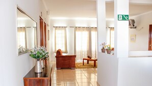 Un hall d’hôtel avec un comptoir d’accueil, un canapé et une petite table sur laquelle est posé un vase de fleurs.