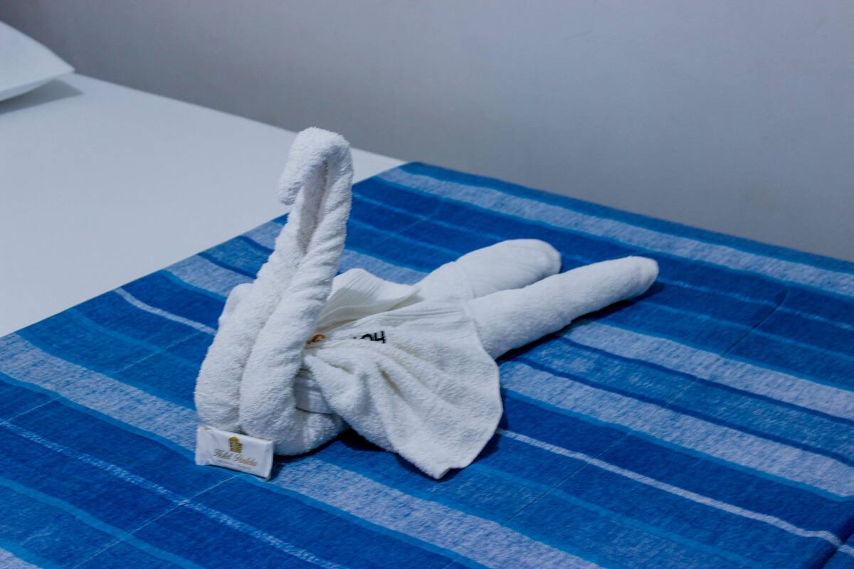 A neatly folded white towel on a blue striped bedspread.