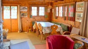 A wooden cabin with a dining table, chairs, and a red chair.