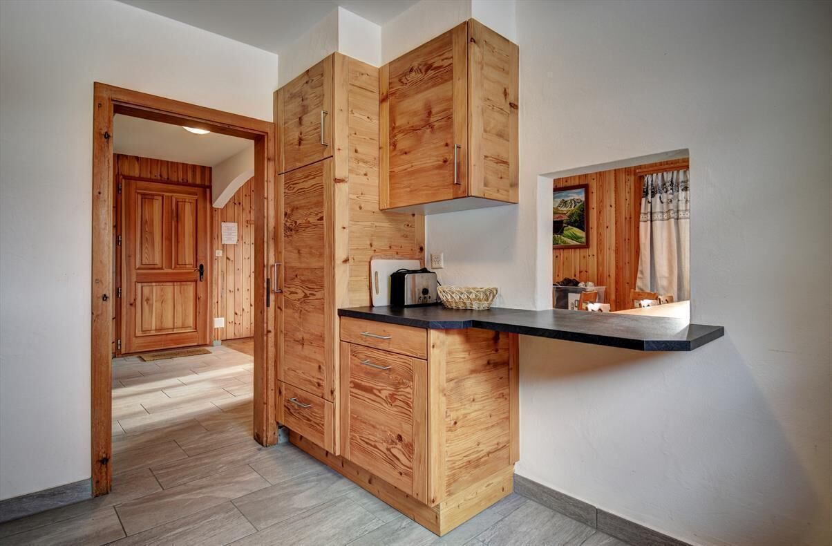 Een moderne keuken met houten kastjes, een zwart aanrecht en een raam met uitzicht op het landschap.