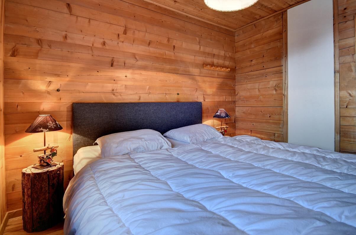 Una stanza con rivestimenti in legno, un letto, due lampade sui comodini e un piccolo tavolino.