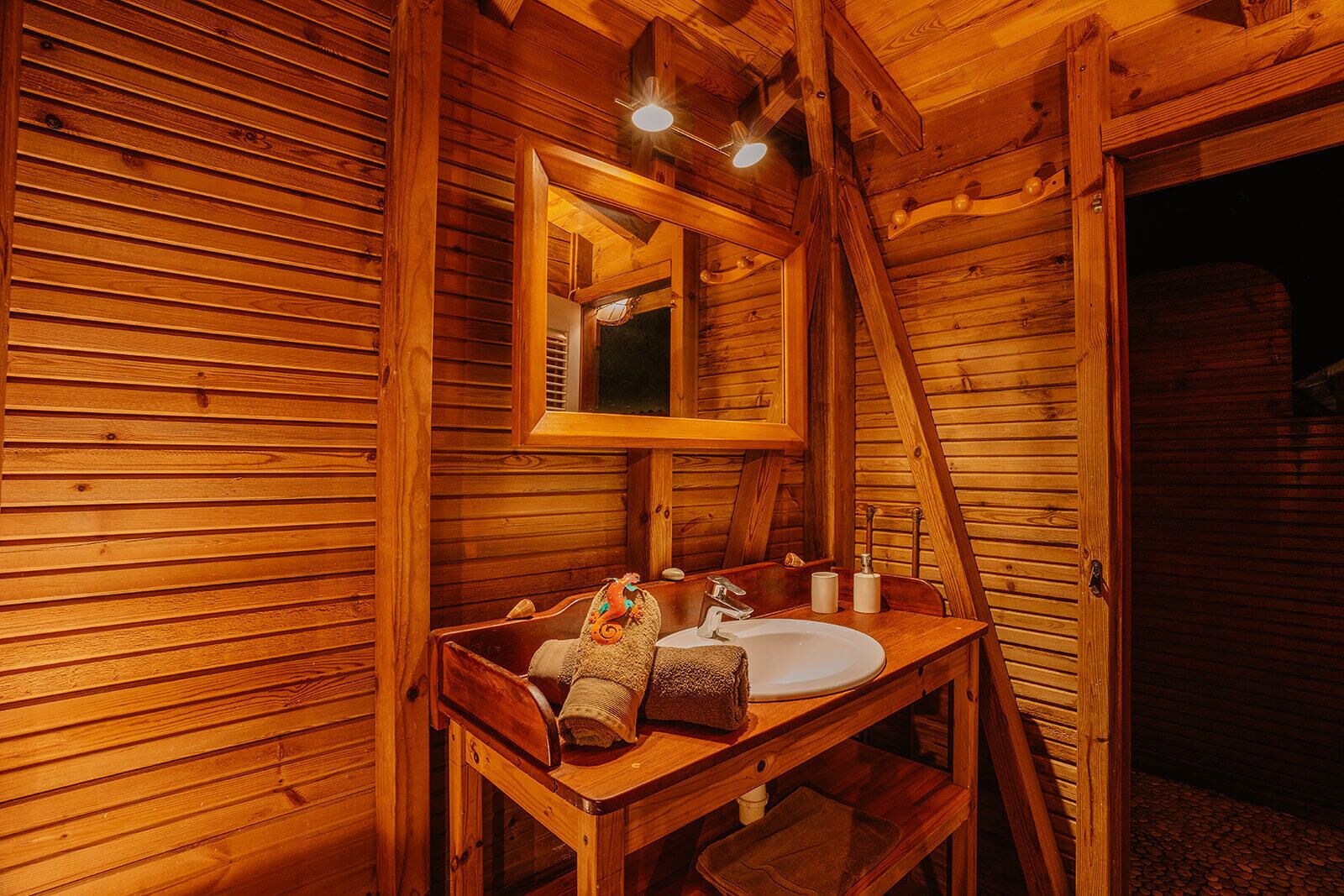 Ein Holzblockbau-Innenraum mit einer hölzernen Bank, einem Waschbecken und einem Spiegel.