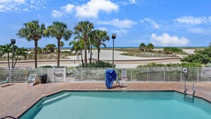 A pool area with a view of the beach and palm trees. - Surf Beach 203 - Gulf Front Condo - ADA (Treasure Island)
