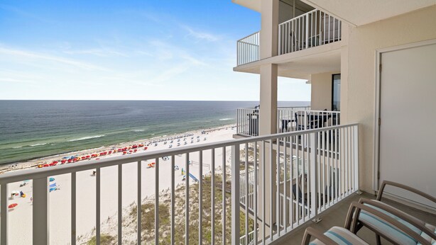 Een balkon met uitzicht op het strand, een zwembadgedeelte en een deur aan de rechterkant.