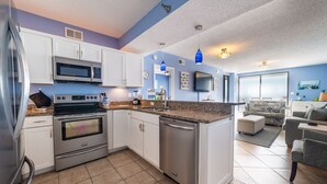 Een moderne keuken met witte kasten, roestvrijstalen apparatuur en een blauwe accentmuur.