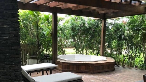 Eine Terrassengrundstück mit Steinböden, einem Whirlpool und Holzmöbeln.
