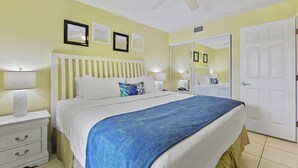 A hotel room with a bed, bedside tables, a mirror, and a door.