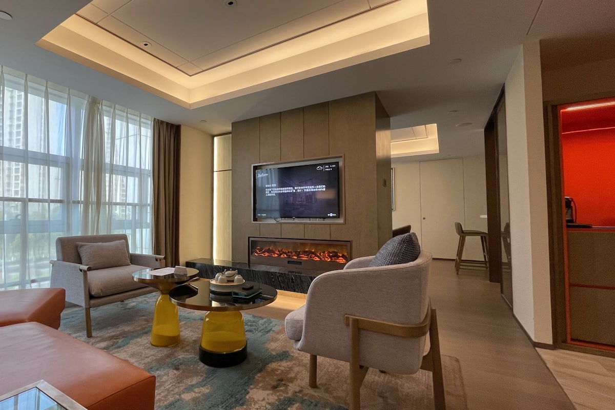 A modern living room with a flat-screen TV, a fireplace, and comfortable seating.