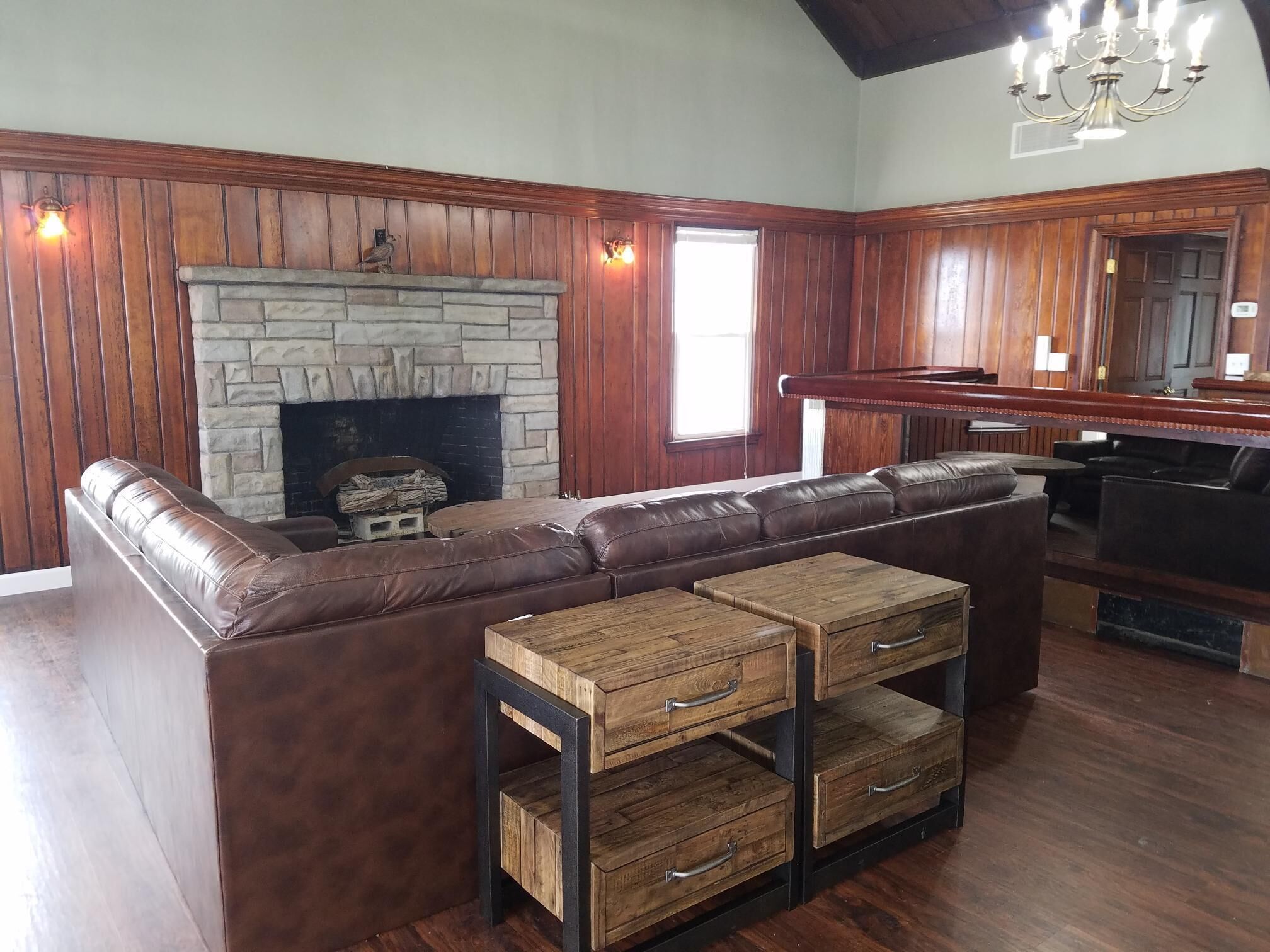 A cozy living room with a stone fireplace, leather sofa, and wooden coffee table.