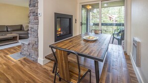 Un comedor con mesa de madera, sillas y una pared de acento de piedra.