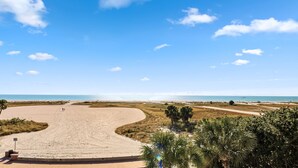 A beach with a curved pathway leading to the water, palm trees, and a clear blue sky. - Surf Beach 406 - Luxury Corner Unit (Treasure Island)
