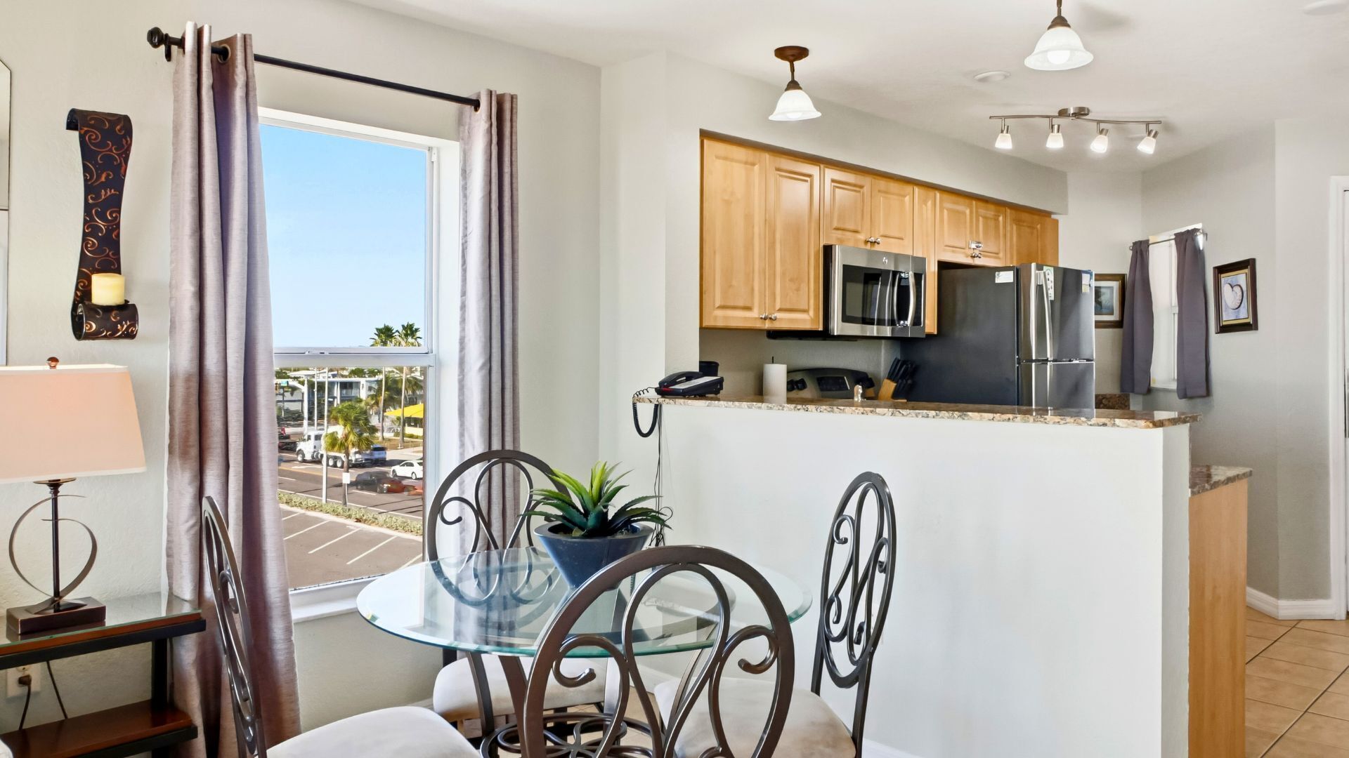 A modern kitchen with wooden cabinets, stainless steel appliances, and a glass dining table.