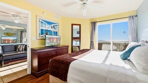 A hotel room with a bed, a TV, a desk, and a balcony with a view of the beach. - Surf Beach 405 - Spectacular Sunsets - Beach Front (Treasure Island)